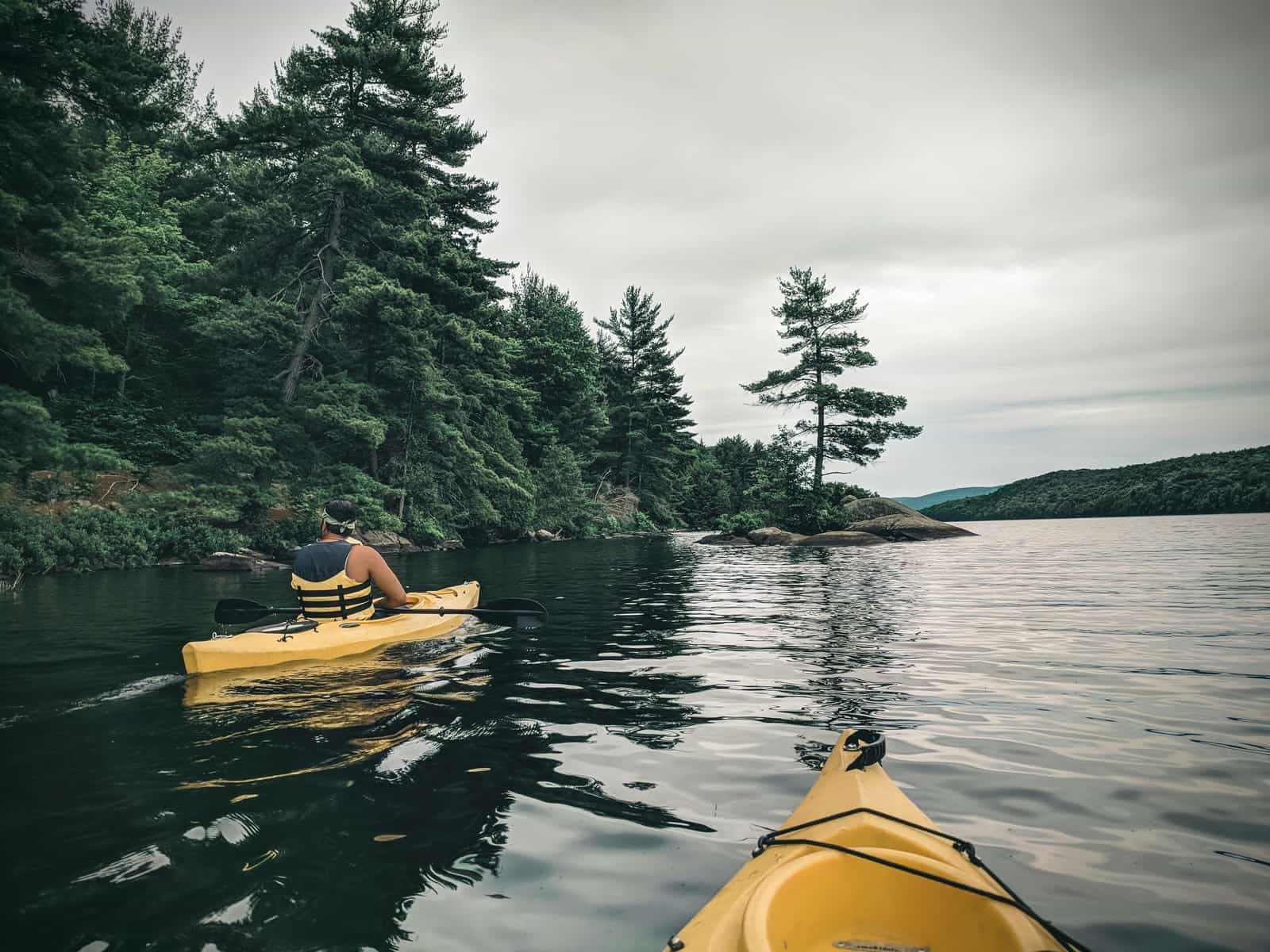 A paddler sitting in a sit-on-top kayak on calm water