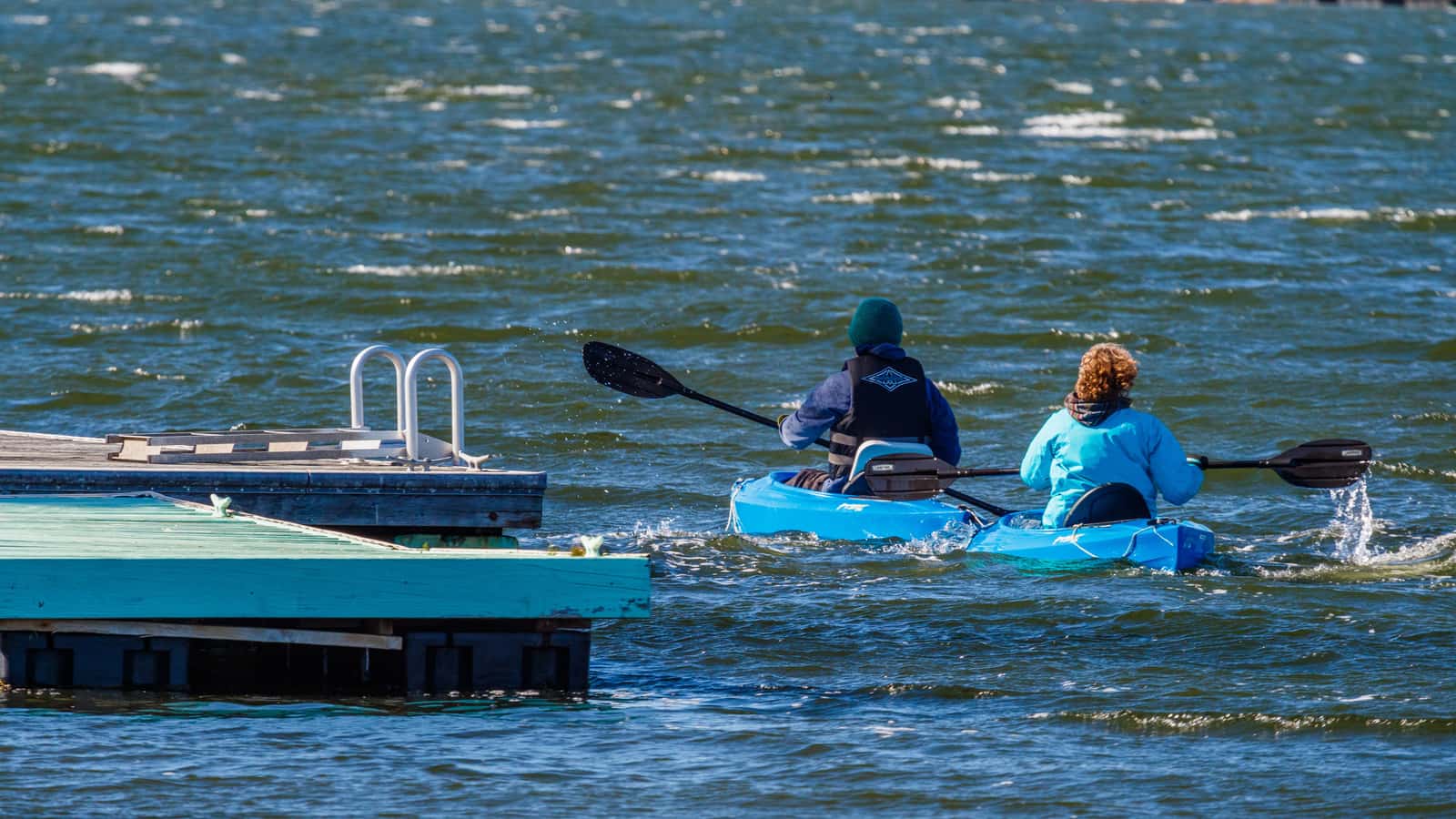 A kayak paddle and life jacket laid out on a wooden dock