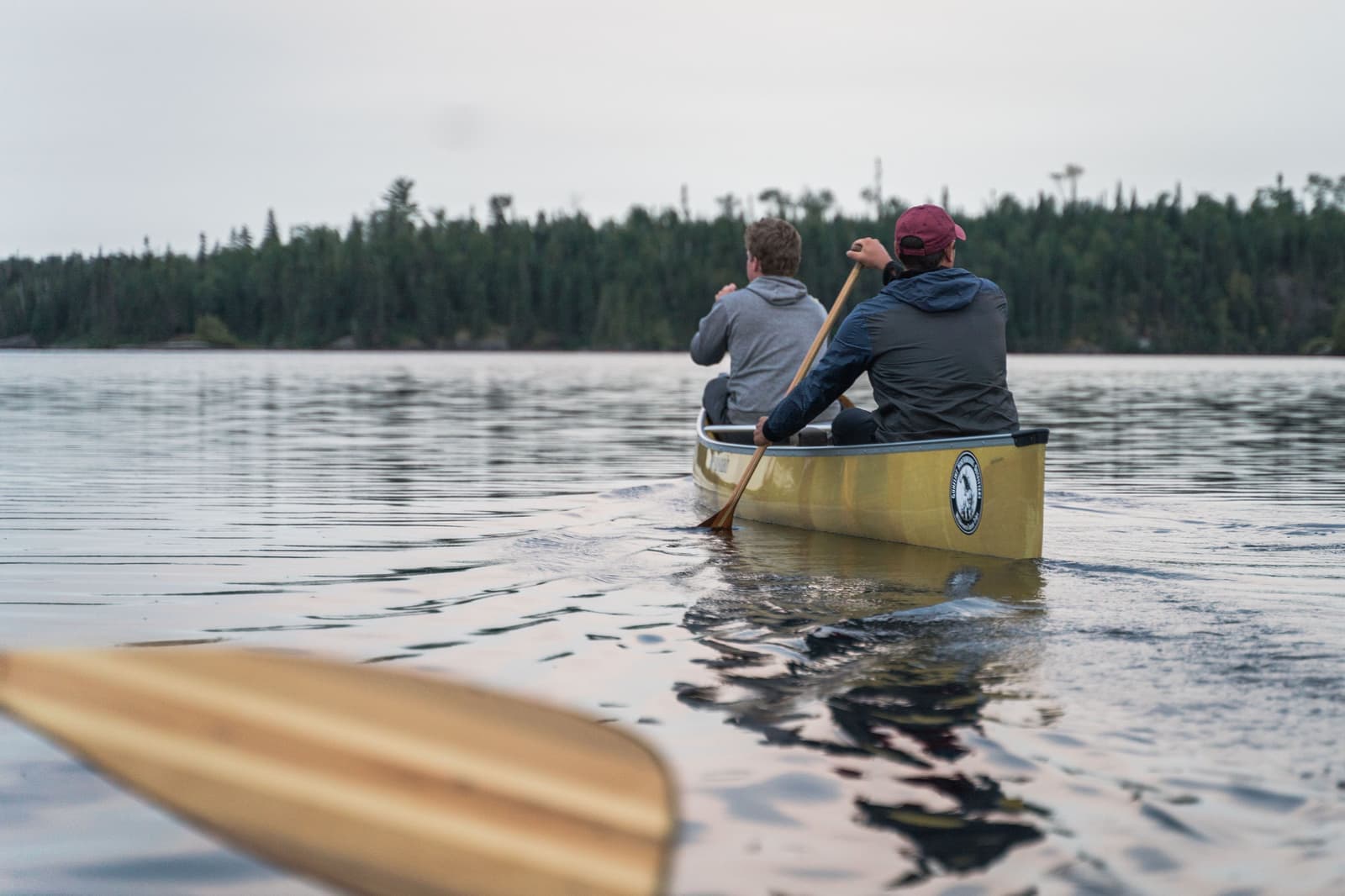 A canoe with paddles resting on a calm lake shore