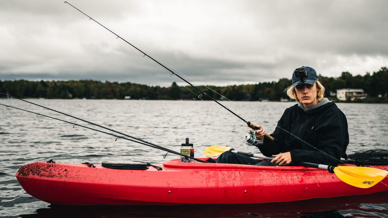 An angler fishing from a red kayak on a calm lake
