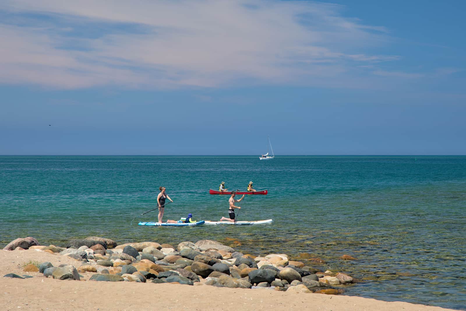 A paddle board and a kayak side by side on the shore