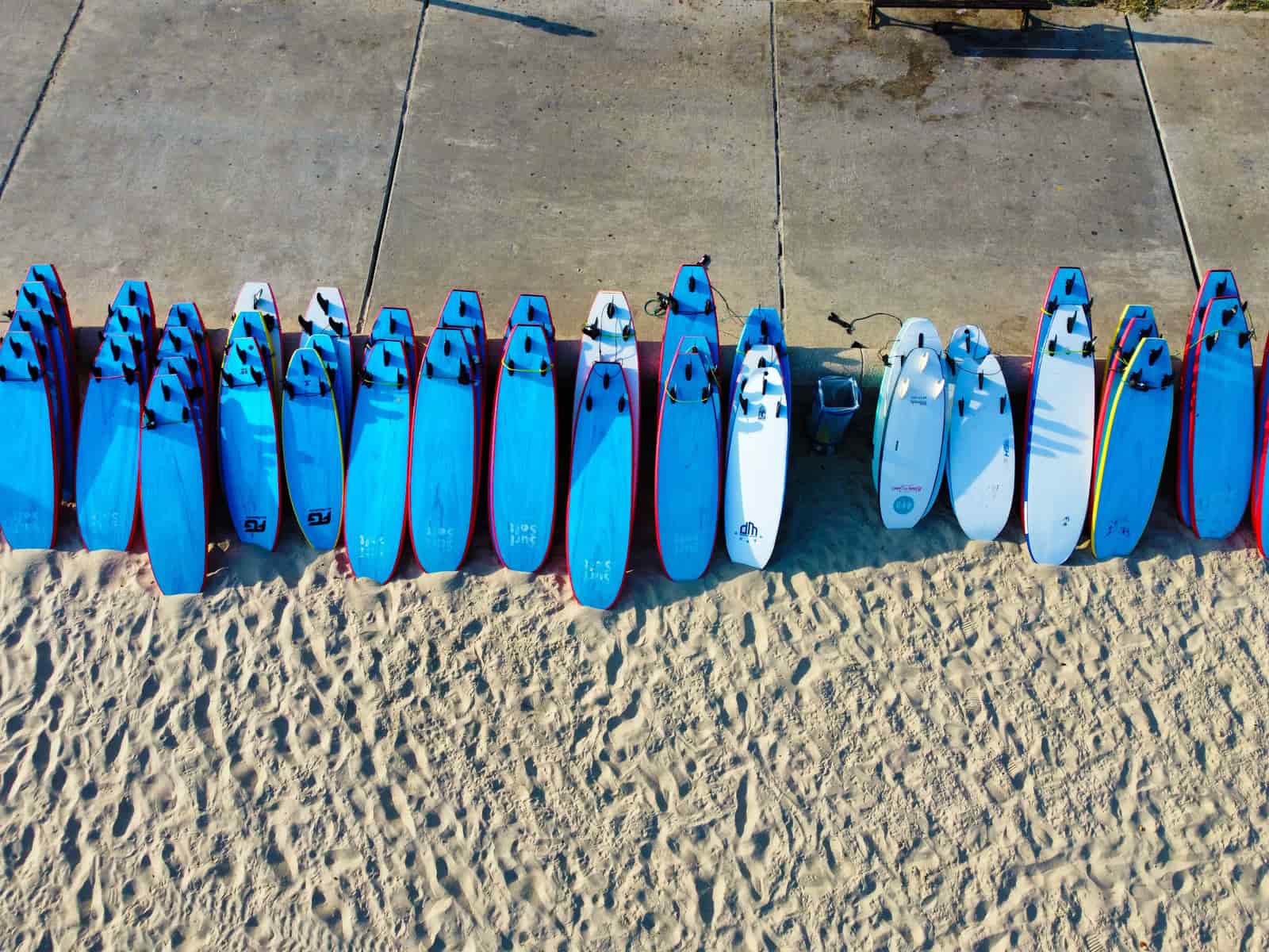 A surfboard and a paddle board on beach sand