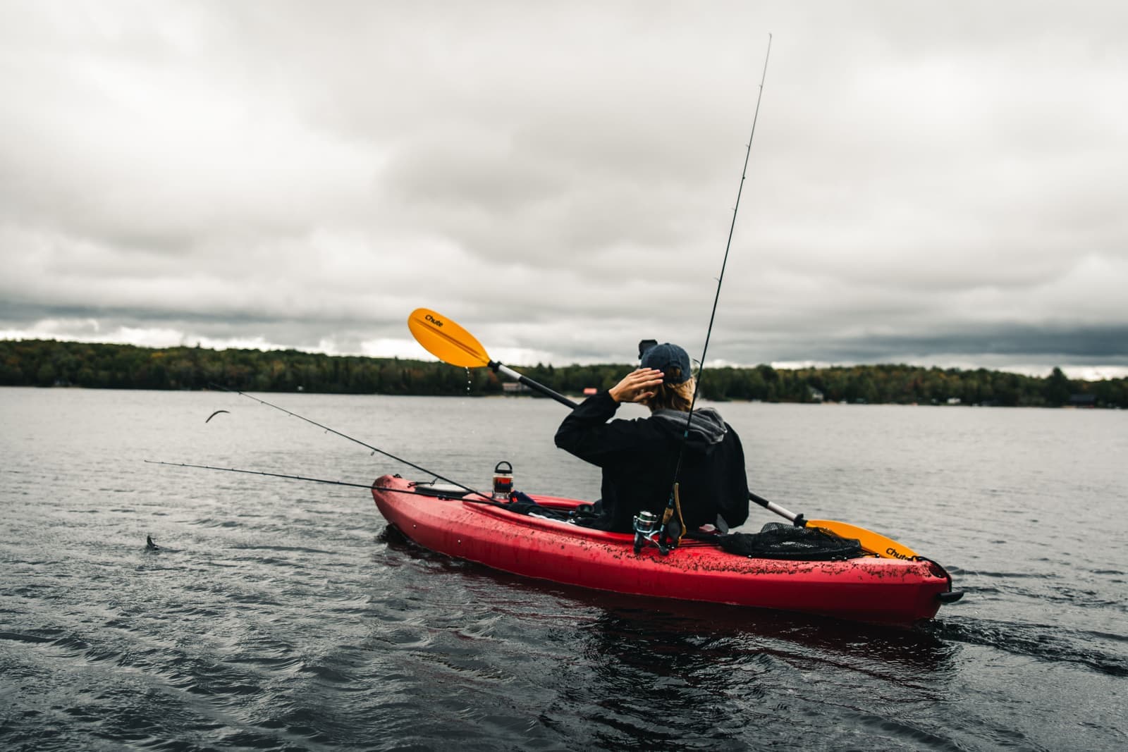 An angler fishing from a sit-on-top kayak on calm water