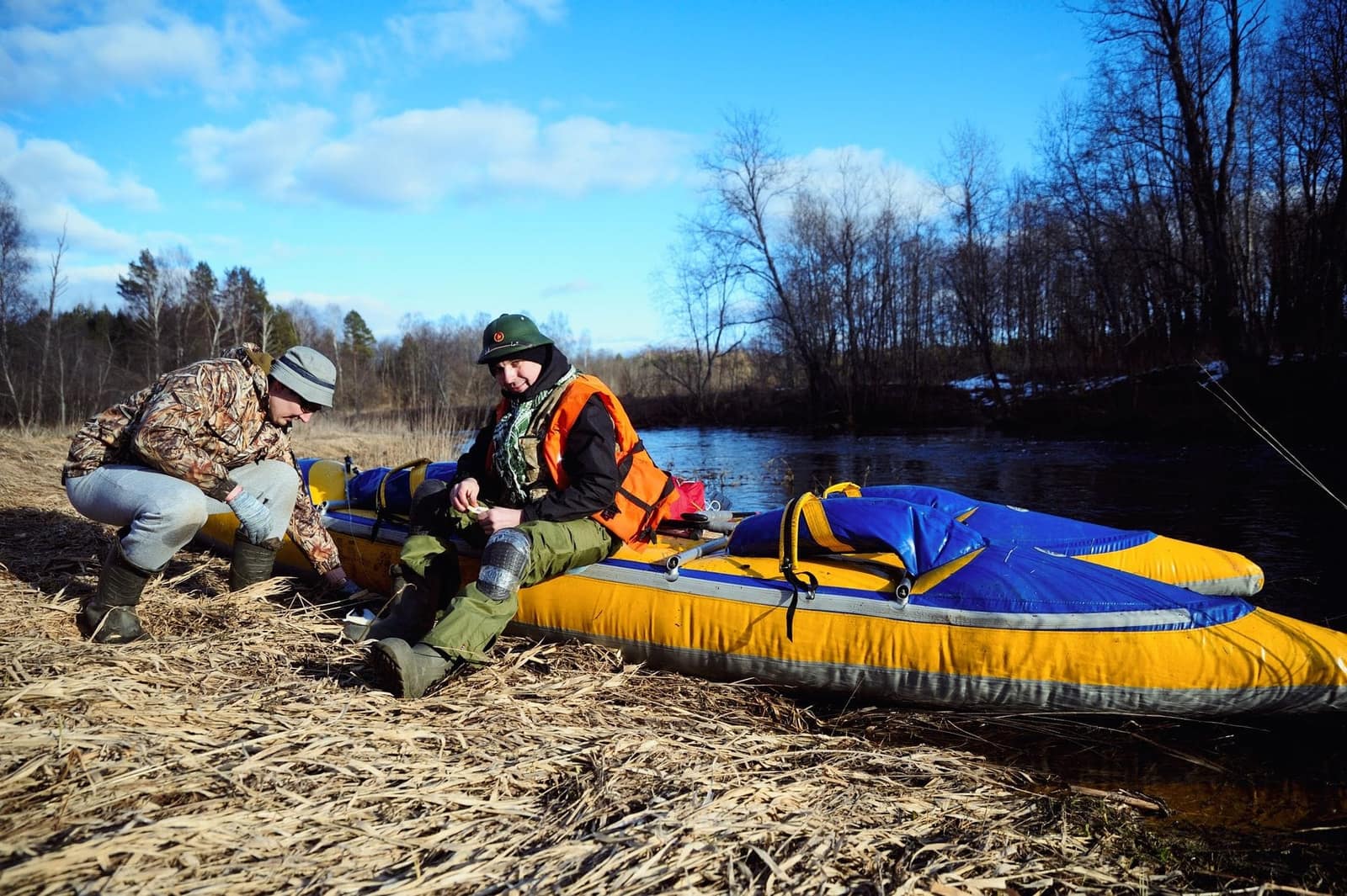 Two paddlers preparing gear beside an inflatable kayak