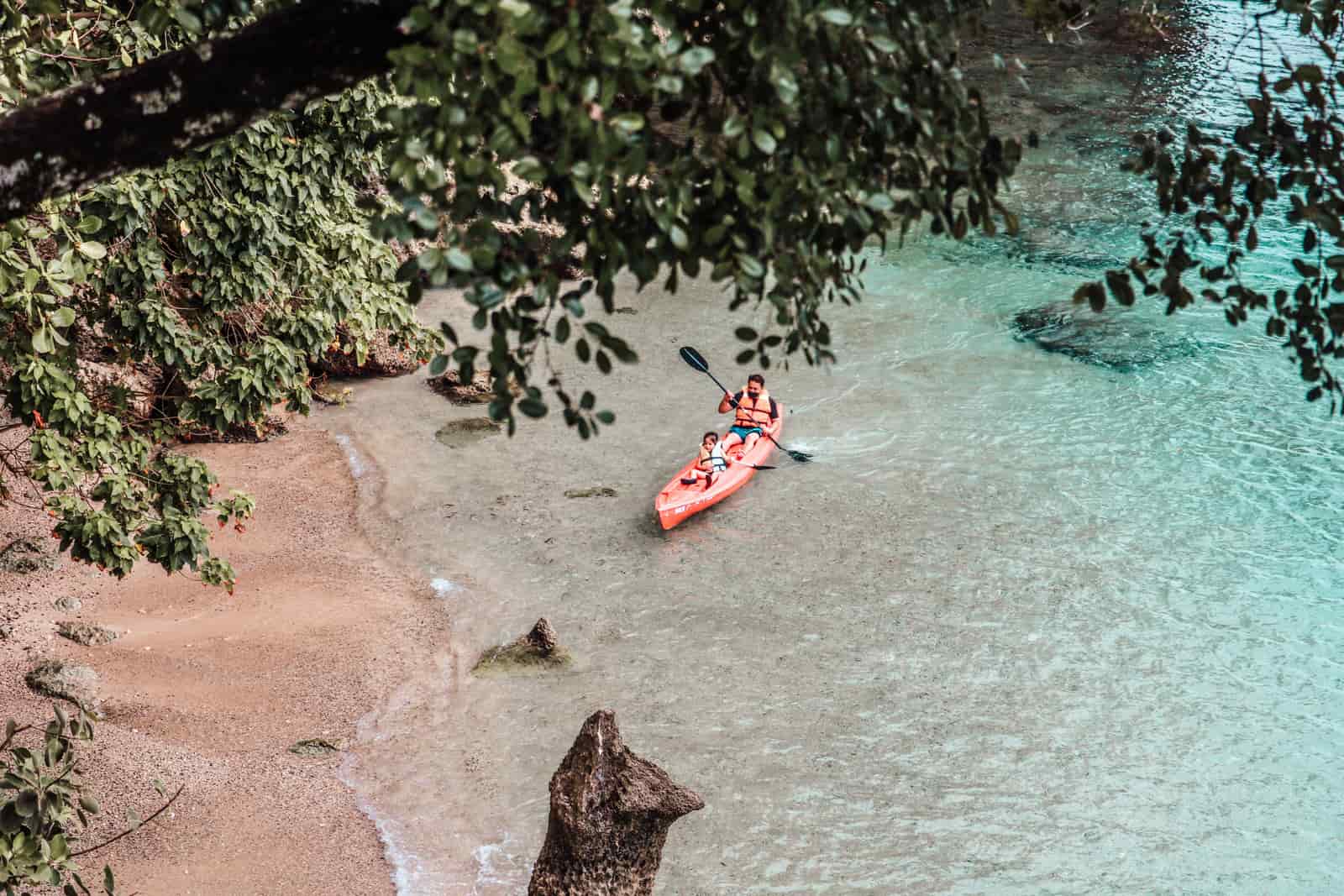 A child paddling a small kayak near the shore