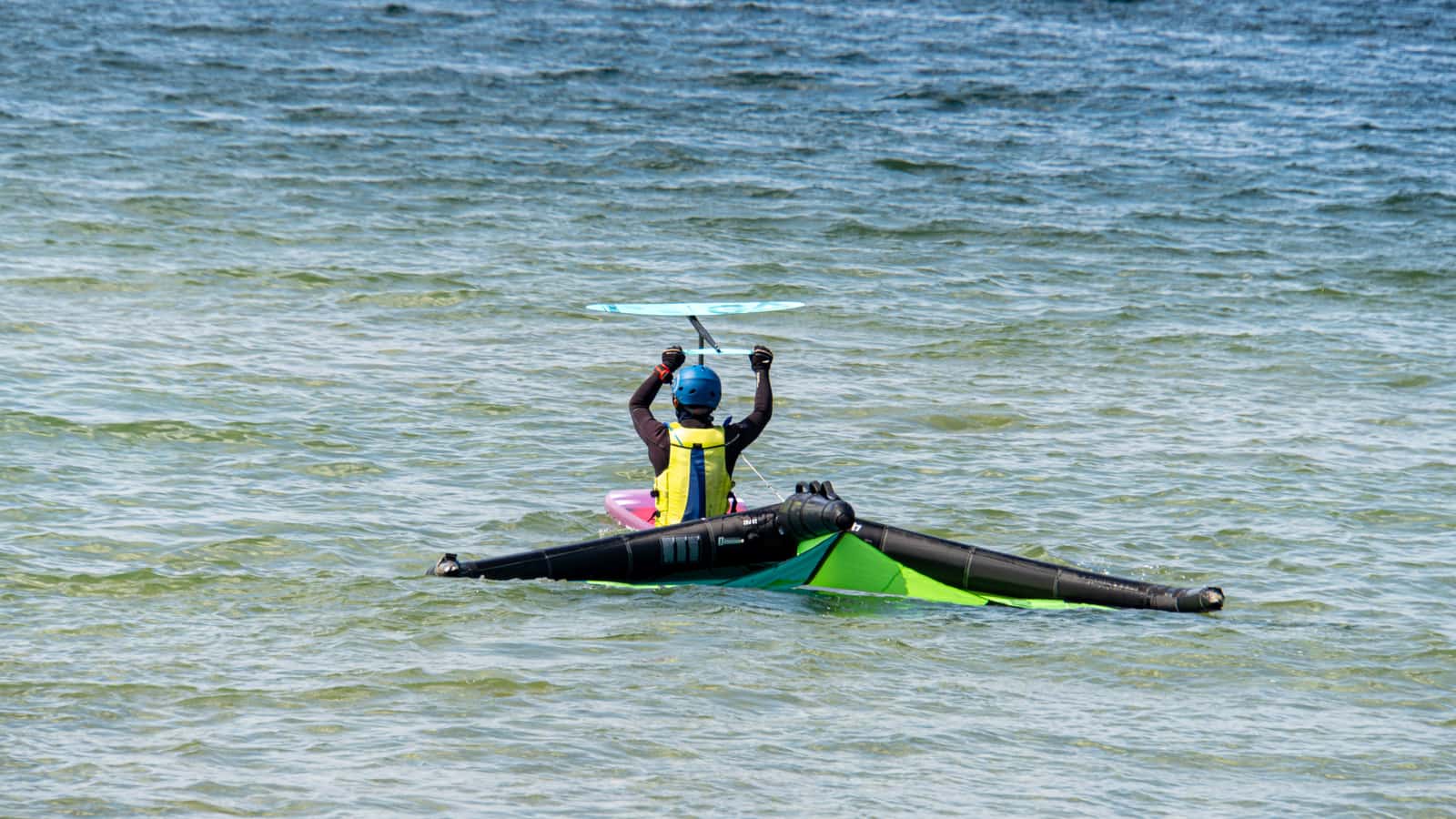 A person carrying a kayak on their shoulder toward the water
