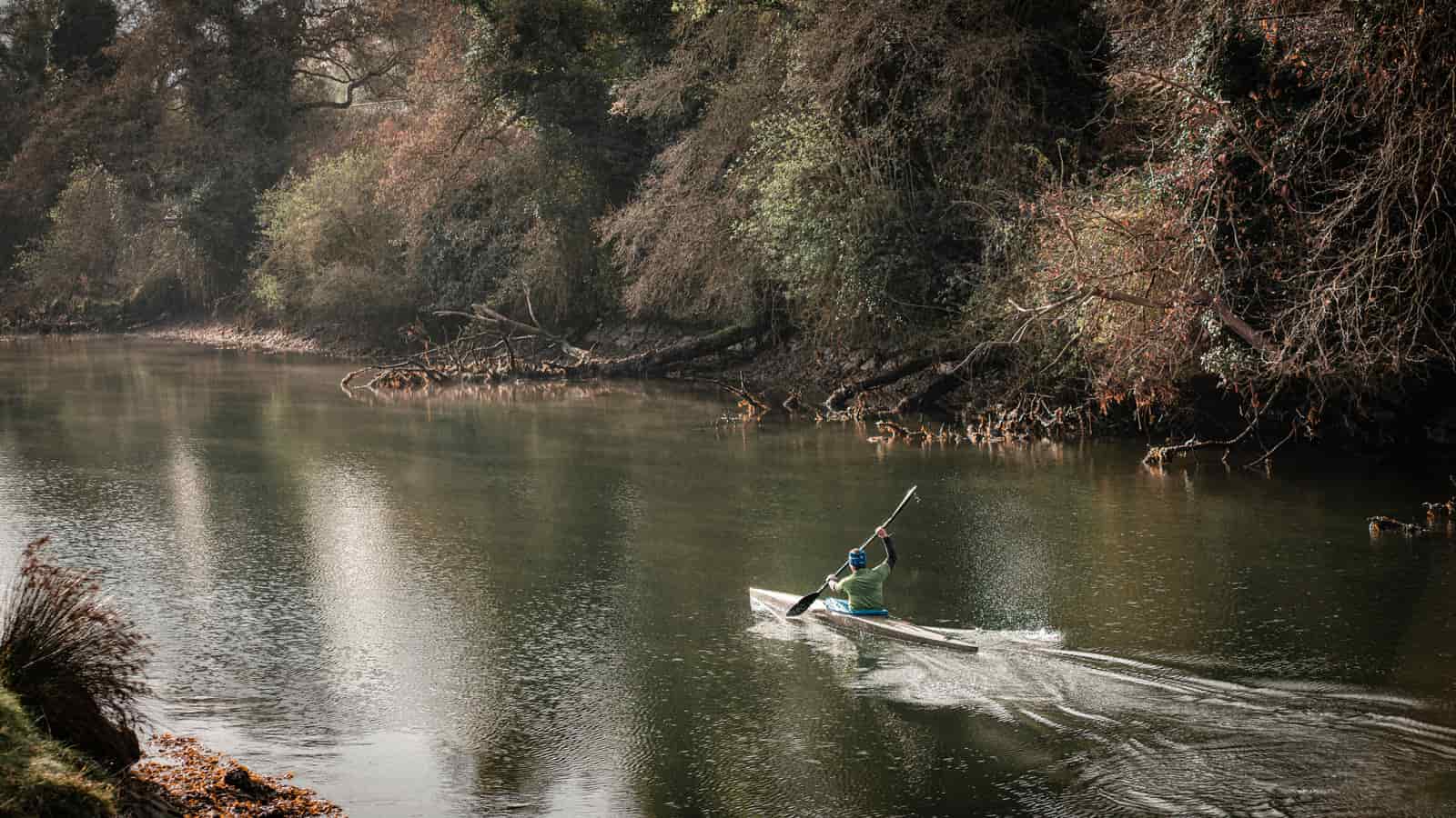 A kayak on a slow tree-lined river