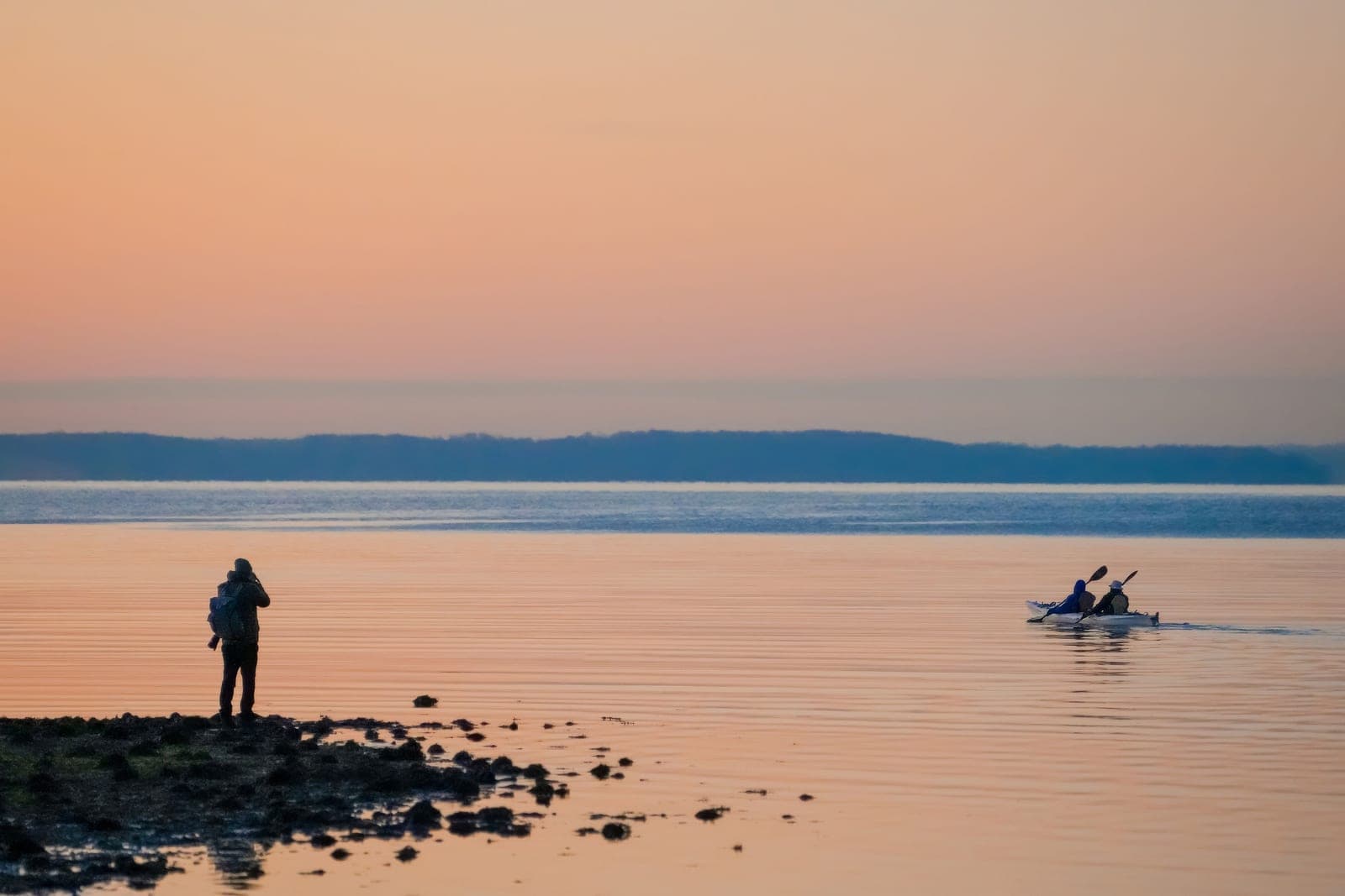 An older couple paddling kayaks on a calm lake