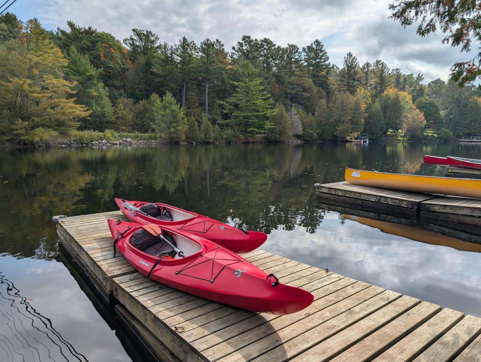Two kayaks on a wooden dock beside a calm lake
