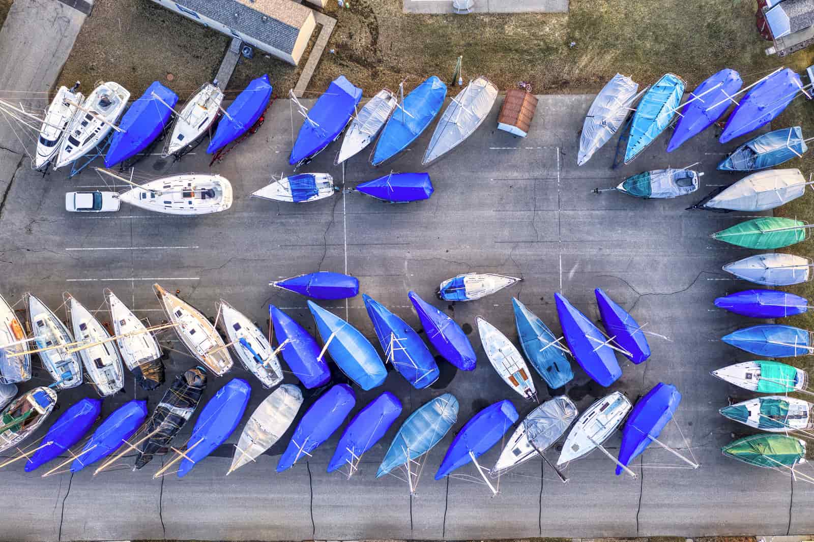 A covered boat in winter storage beside a lake
