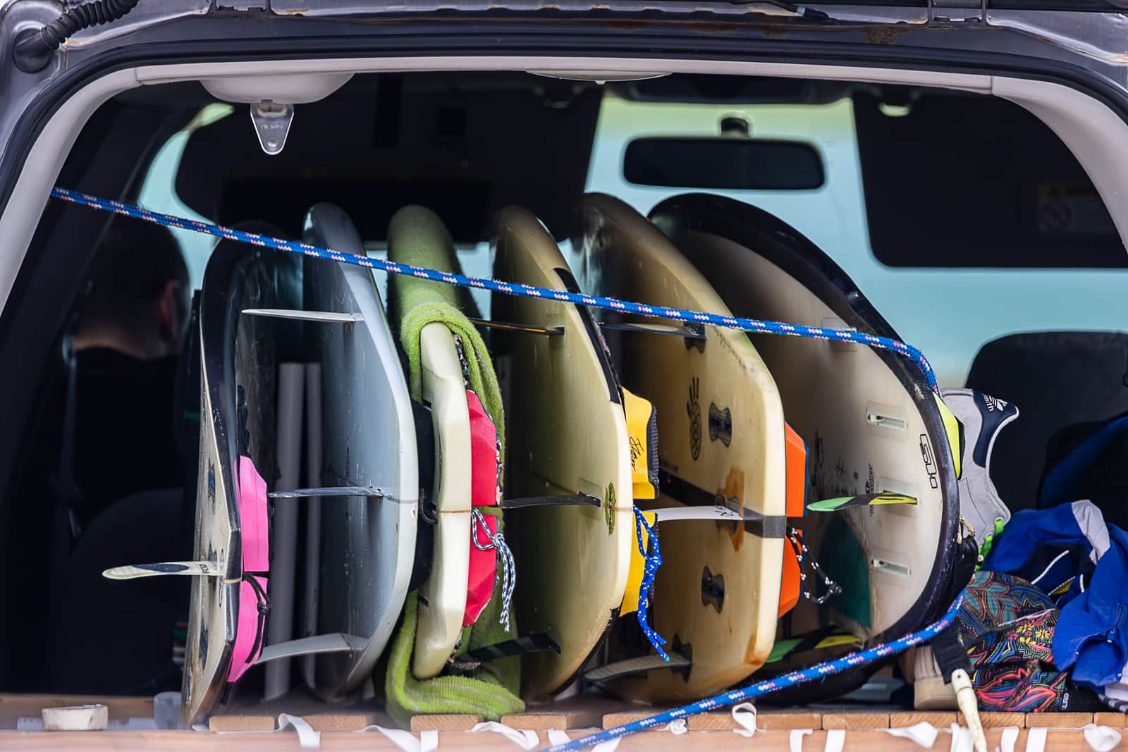 A paddle board packed into a rucksack beside a car