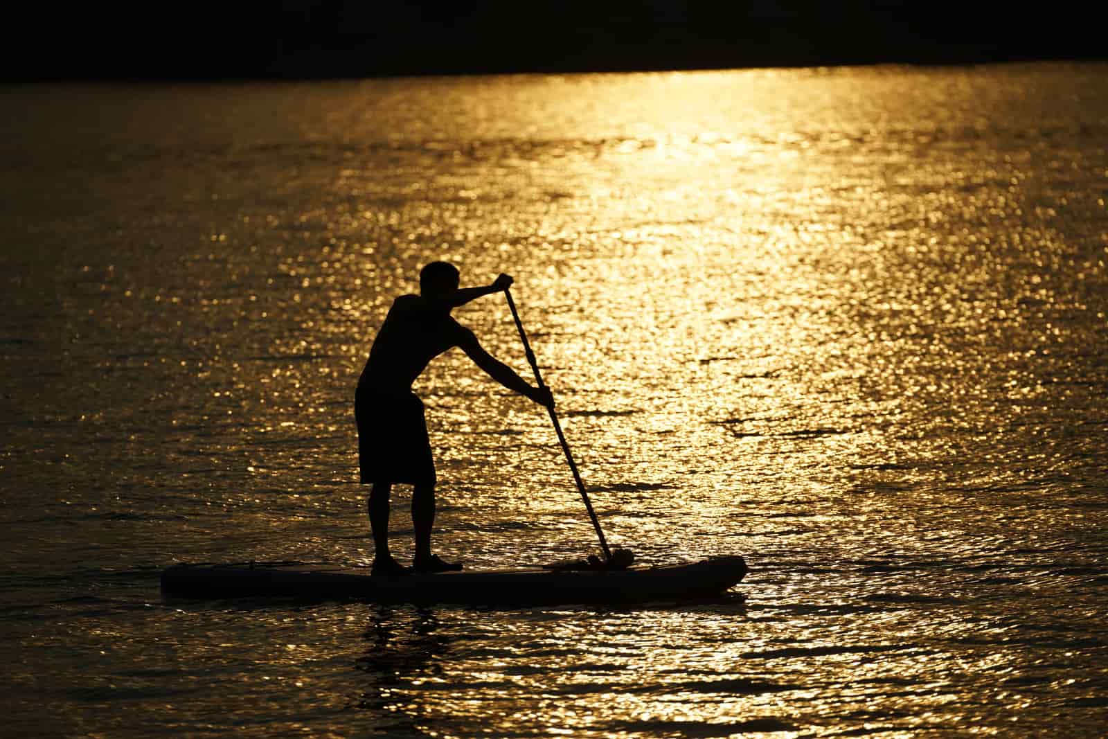 An inflatable paddle board on the water at golden hour