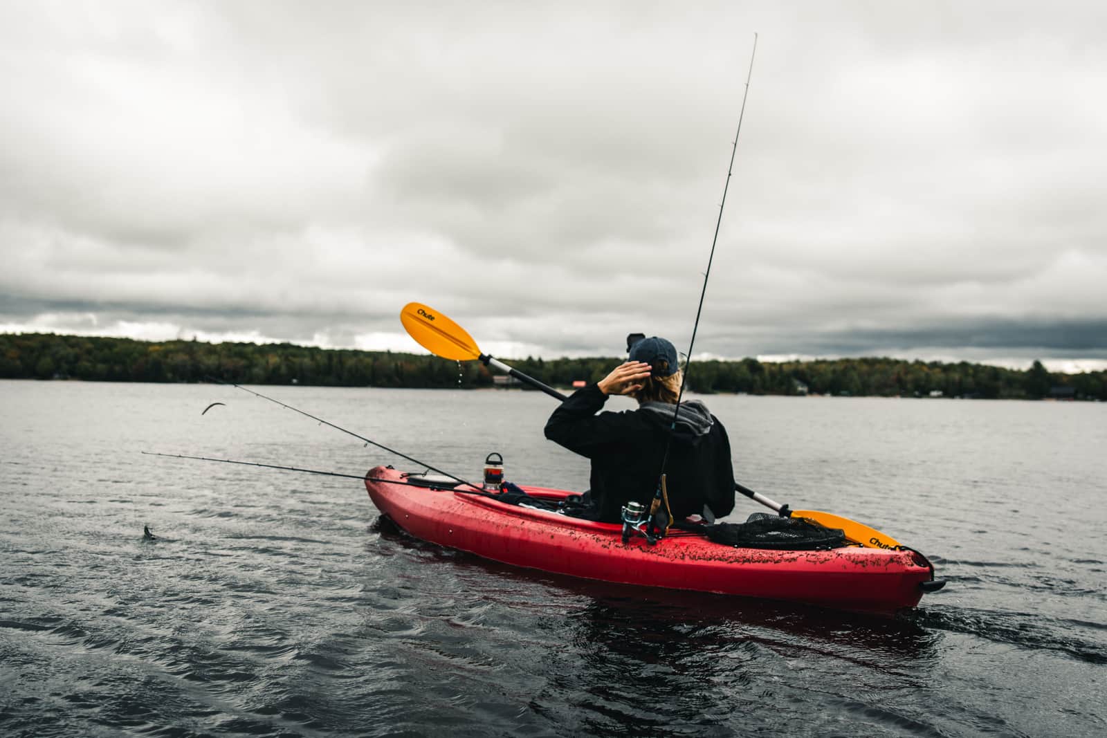 An angler fishing from a wide paddle board on flat water