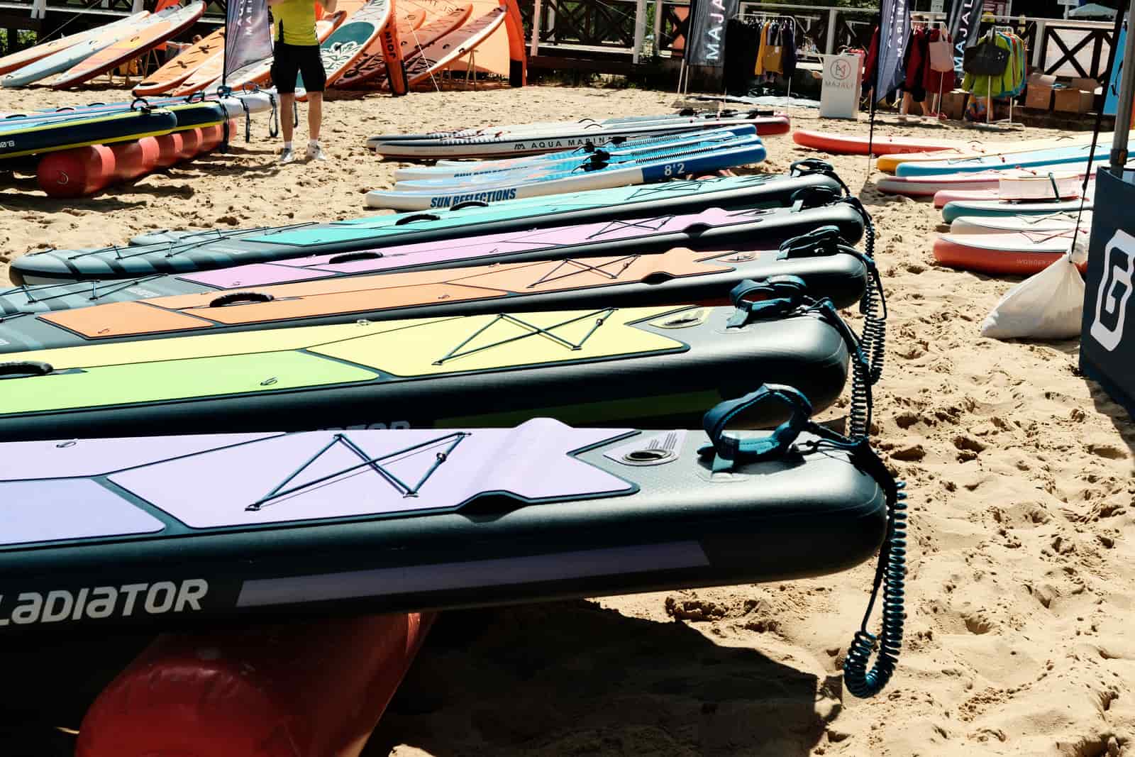 An inflatable paddle board rolled into its carry bag beside the water