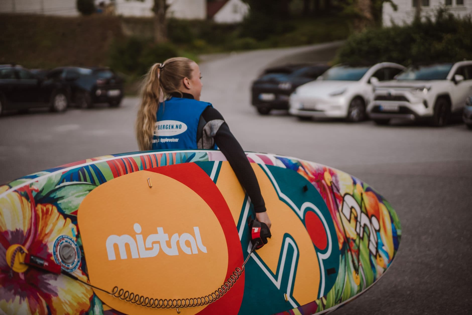 A paddler carrying a paddle board across a parking lot