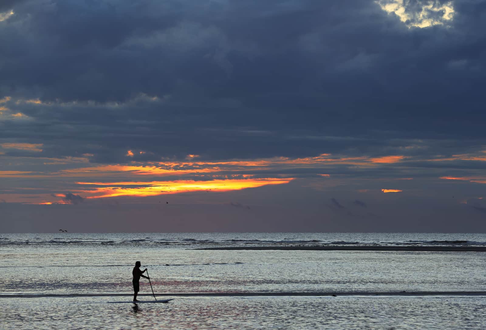A paddle board resting flat on still water at sunrise