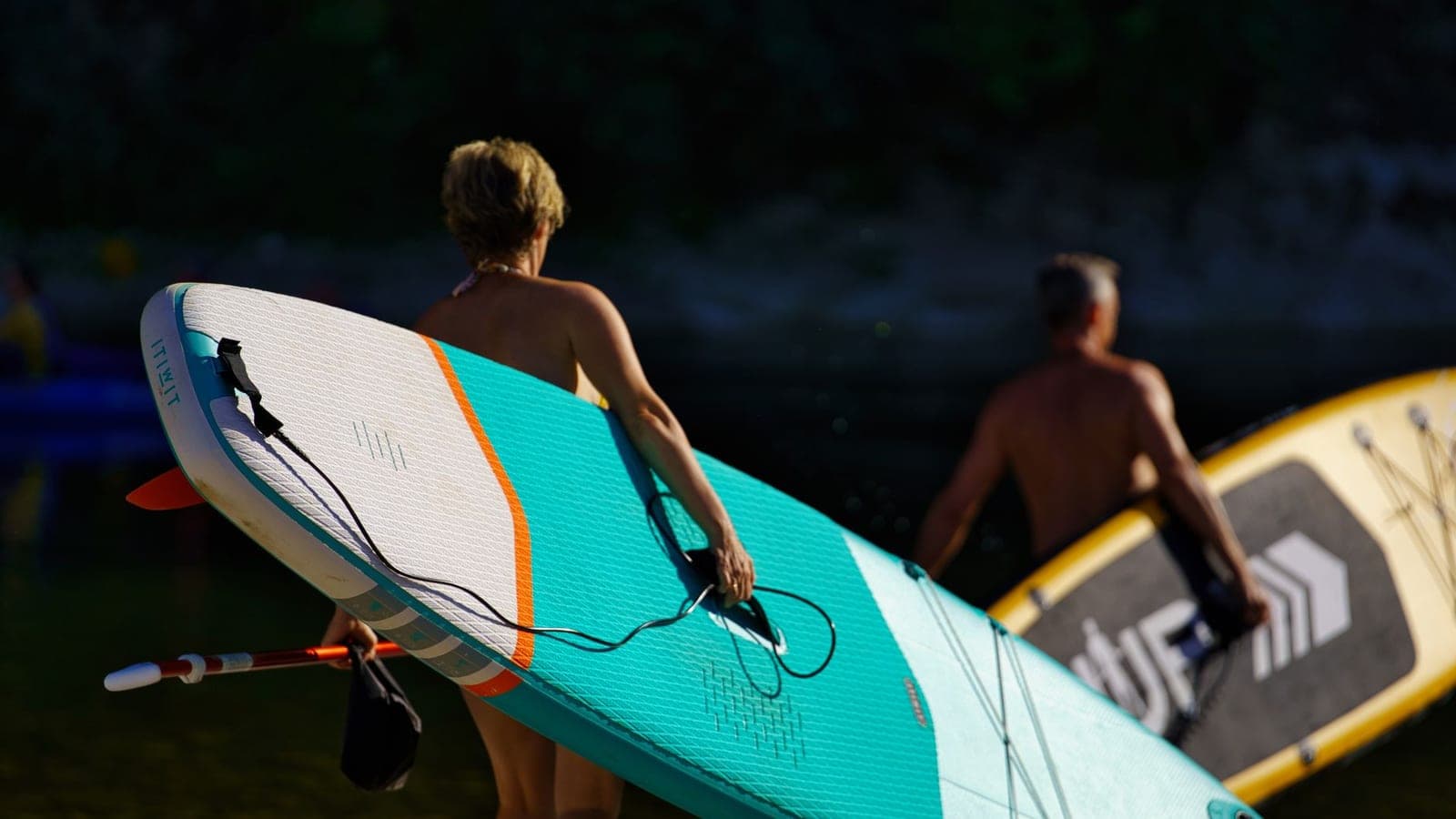 Two adults paddle boarding together on a lake on a sunny day