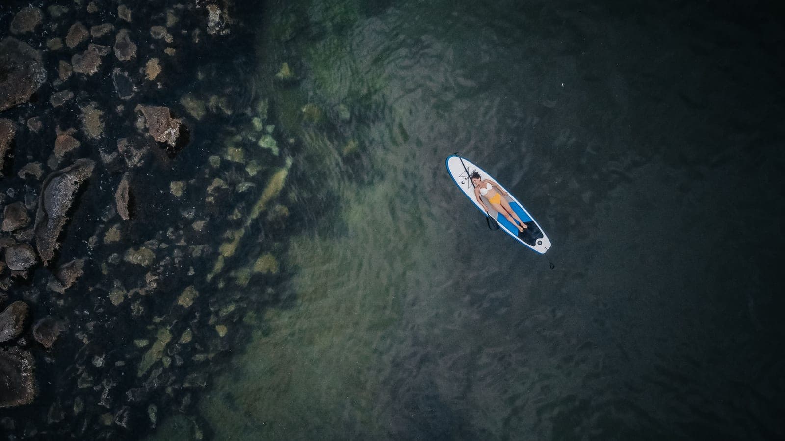 A person holding a yoga pose on a paddle board on still water